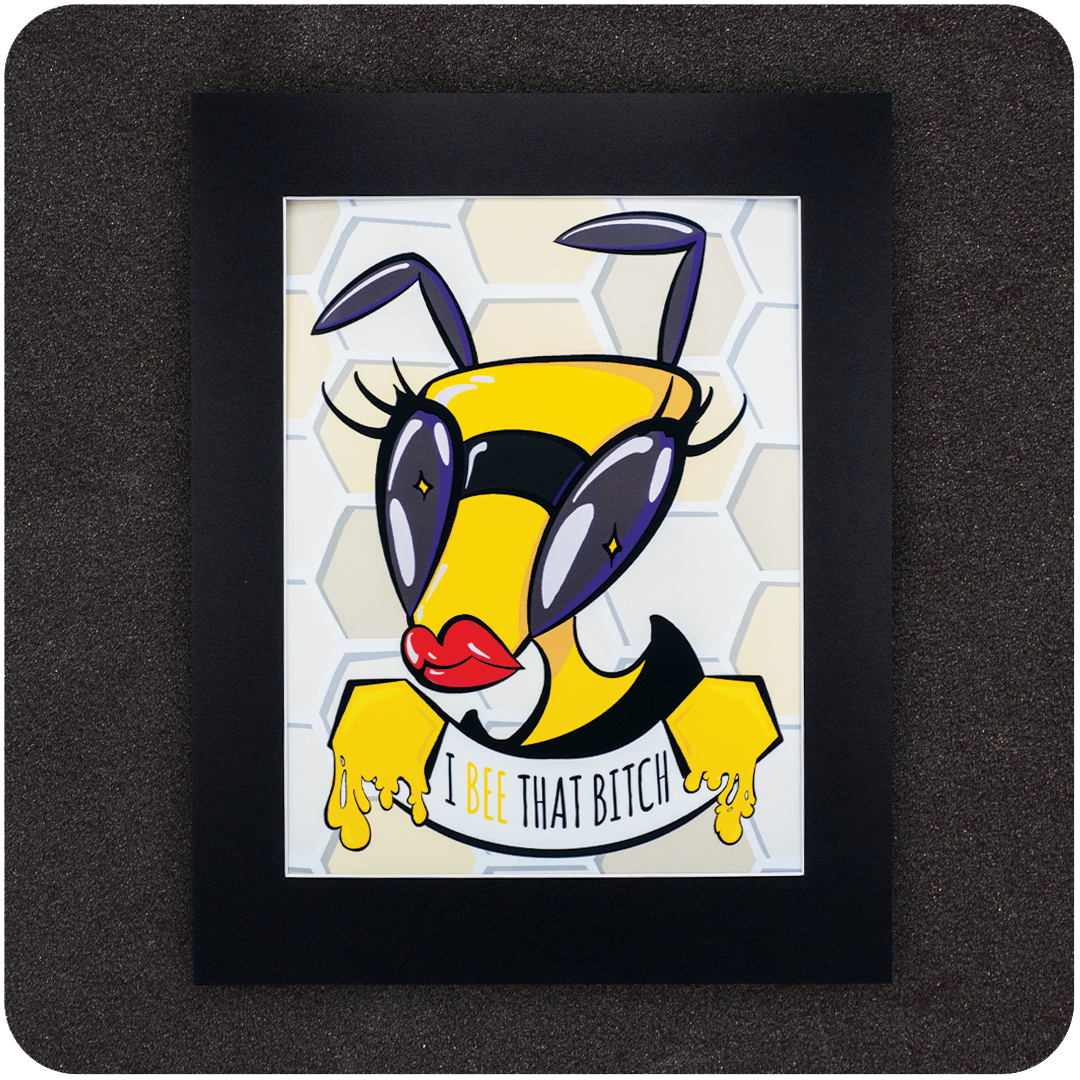 Framed art print featuring a bold cartoon bee with red lips, oversized purple eyes, and dramatic lashes, posed confidently in front of a honeycomb background. Below the bee, the text reads “I Bee That Bitch” in a playful font with honey dripping from its hands.