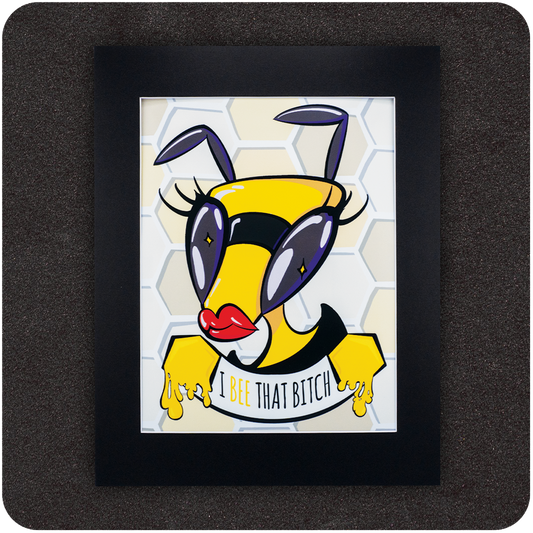 Framed art print featuring a bold cartoon bee with red lips, oversized purple eyes, and dramatic lashes, posed confidently in front of a honeycomb background. Below the bee, the text reads “I Bee That Bitch” in a playful font with honey dripping from its hands.