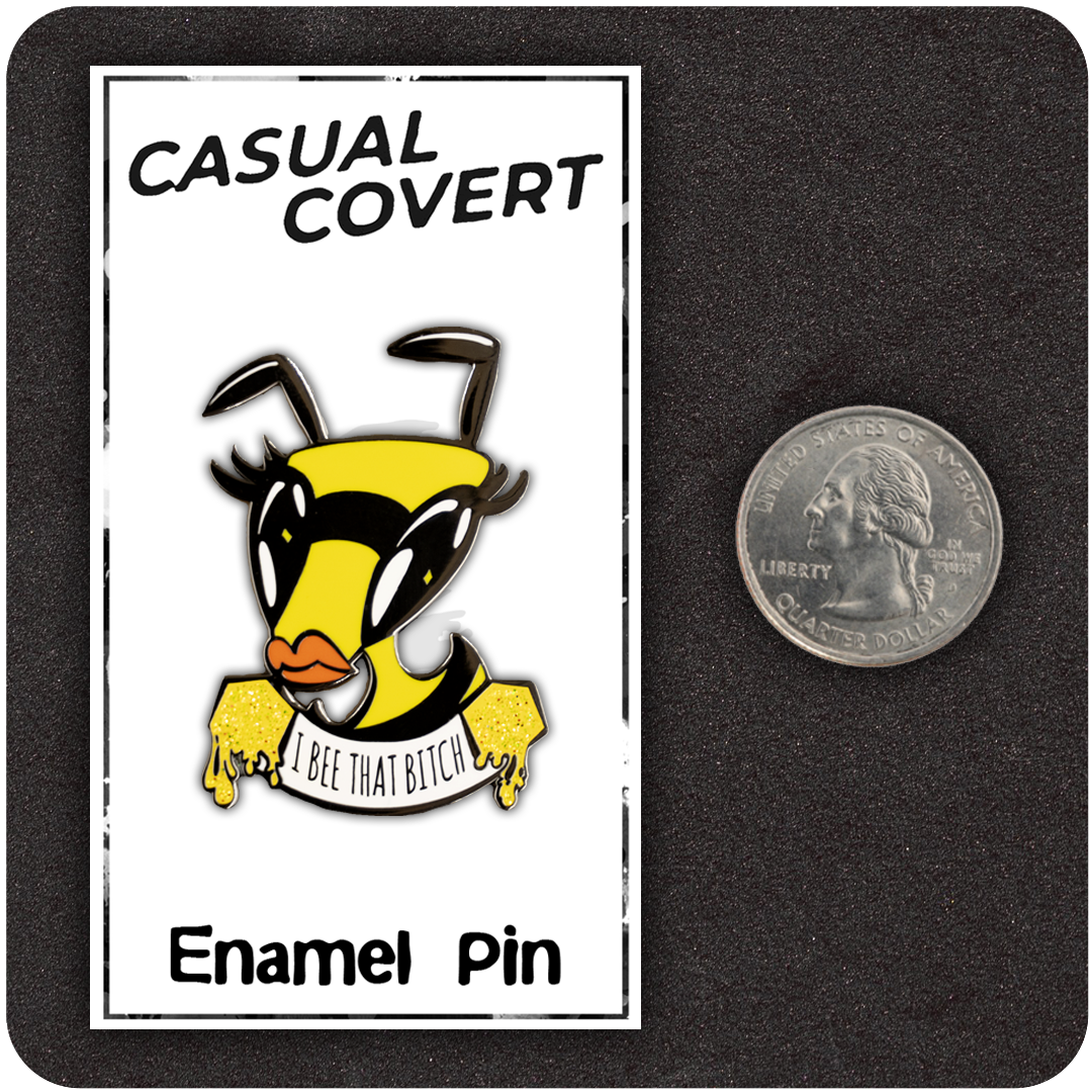 The Casual Covert I Bee That Bitch Enamel Pin next to a quarter to show it's scale.