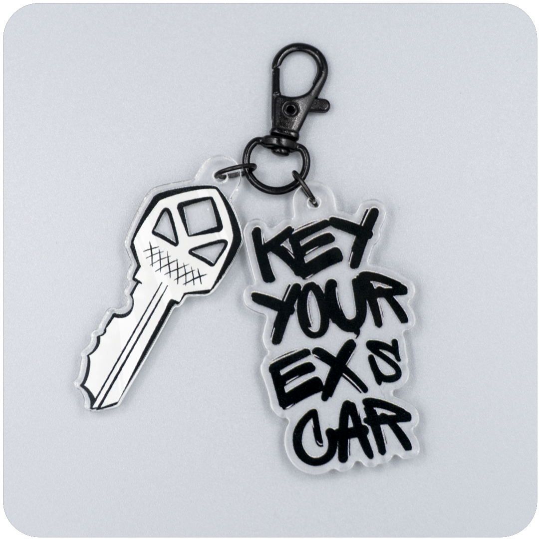 Acrylic keychain featuring a jagged illustrated key and bold black graffiti-style text reading “Key Your Ex’s Car,” attached to a black metal lobster clasp on a neutral gray background.