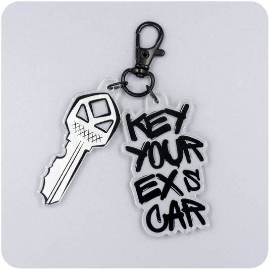 Acrylic keychain featuring a jagged illustrated key and bold black graffiti-style text reading “Key Your Ex’s Car,” attached to a black metal lobster clasp on a neutral gray background.