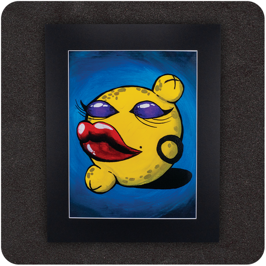 Colorful framed art print featuring a bold, anthropomorphic yellow lemon with exaggerated red lips, purple eyeshadow, hoop earring, and flirty expression against a rich blue background. Presented in a sleek black mat for a gallery-style finish.