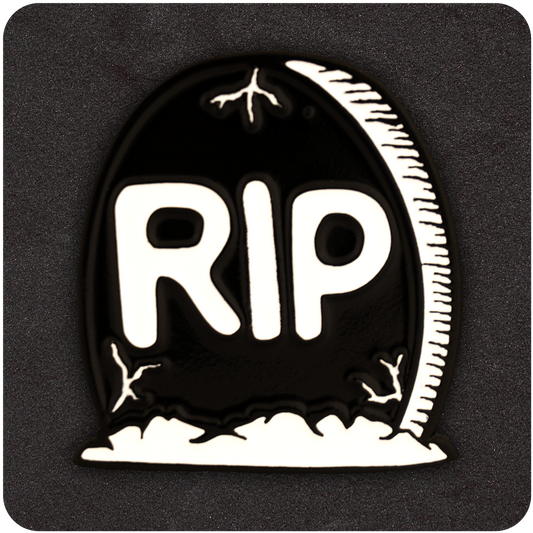 Black and white enamel pin shaped like a tombstone with bold “RIP” lettering and cracked detailing, displayed on a dark textured background.