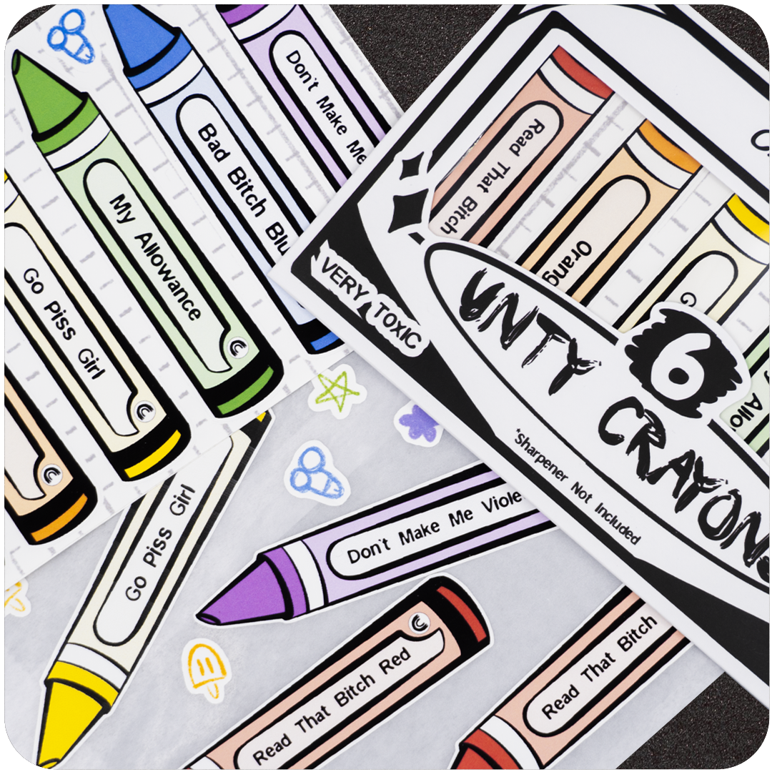 A close-up shot of the Unty Crayon sticker set by Casual Covert. The image displays multiple colorful crayon-shaped stickers scattered across the frame, each labeled with cheeky names like “Go Piss Girl,” “Bad Bitch Blue,” and “Don’t Make Me Violet.” The packaging, marked “VERY TOXIC” and “Sharpener Not Included,” is partially visible in the corner, giving a playful, rebellious vibe.