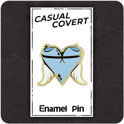Angel Tits enamel pin on branded Casual Covert card backing, featuring a heart-shaped design made from two light blue cartoon breasts with halos, white wings, and gold trim detailing.