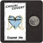 The Casual Covert Angel Tits Enamel Pin next to a quarter to show the enamel pin's relative scale.
