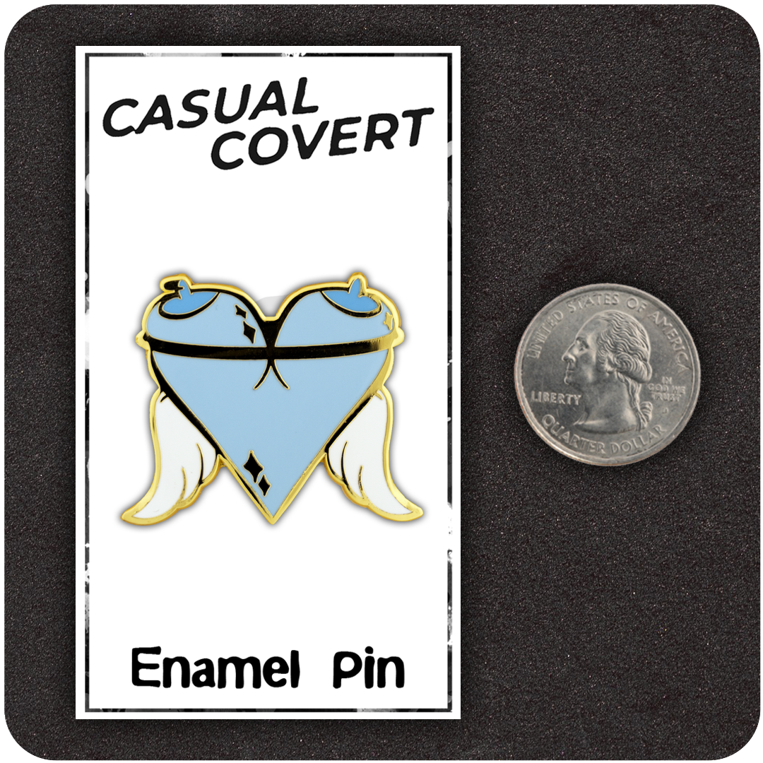 The Casual Covert Angel Tits Enamel Pin next to a quarter to show the enamel pin's relative scale.