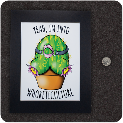 Framed art print featuring a cartoon cactus shaped like a curvy backside with a pink ball gag and leather harness, planted in a pot with purple flowers. Above and below the cactus, the text reads “Yeah, I’m Into WHORETICULTURE.” Displayed on a black background next to a U.S. quarter for scale.