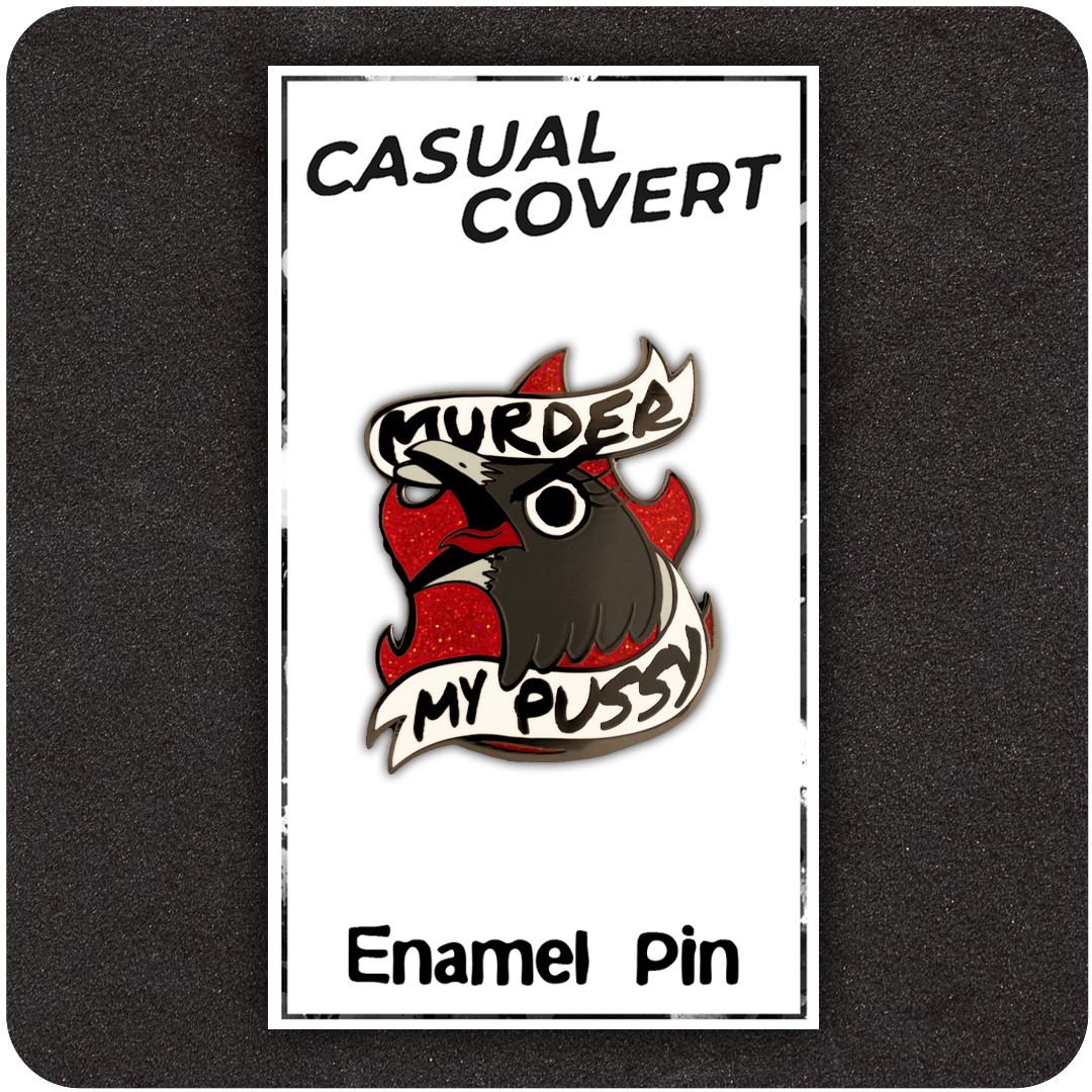 The Casual Covert Murder My Pussy Enamel Pin on the backing card that it is shipped with.