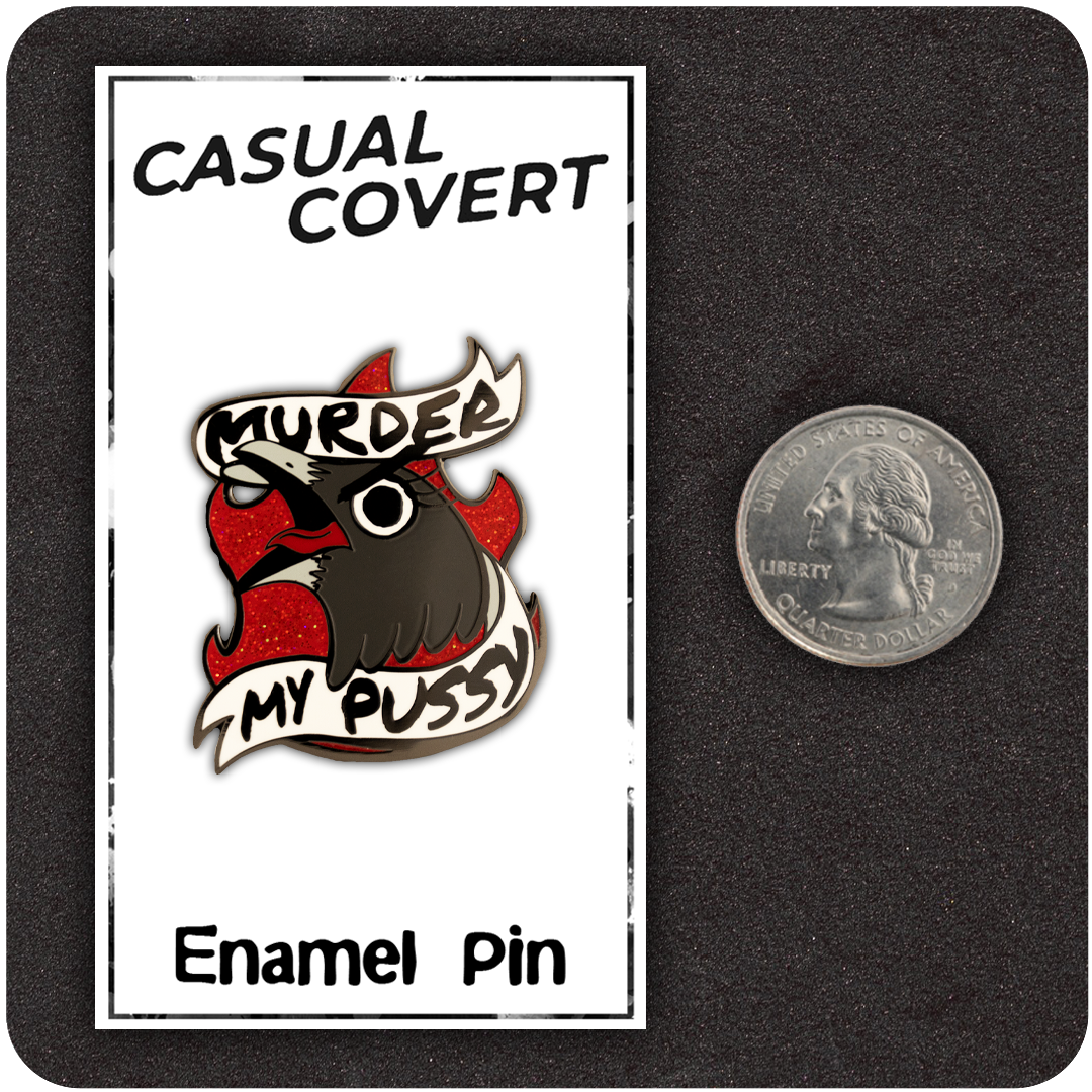 The Casual Covert Murder My Pussy Enamel Pin next to a quarter to show it's scale. 