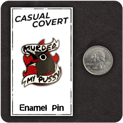 Funny enamel pin of a screaming cartoon bird with a banner that reads “Murder My Pussy,” set against red glitter flames. Displayed on a Casual Covert backing card next to a US quarter for size comparison.