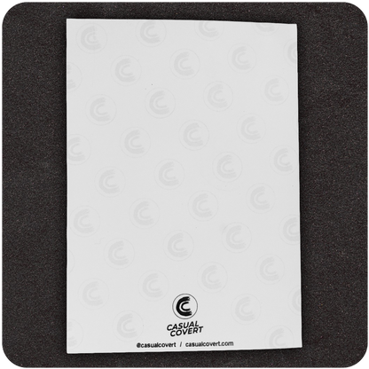 Back side of Casual Covert 5x7 greeting card featuring subtle repeating logo watermark pattern, bold black Casual Covert logo at the bottom center, and brand handle and website — sleek and professional card backing for edgy stationery.
