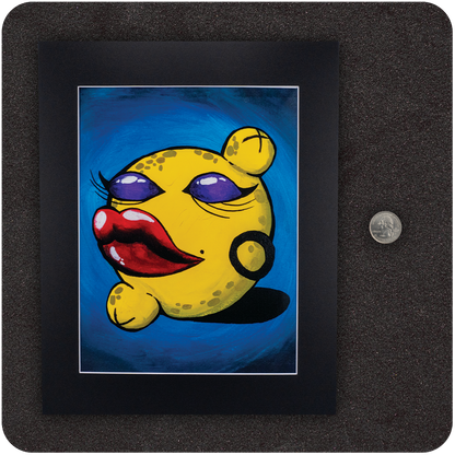 Framed art print titled “Pussy Pop Lemon Drop” featuring a sassy anthropomorphic lemon with red lips and purple eyeshadow, shown with a U.S. quarter for size reference. Black matted frame rests on a textured black surface.
