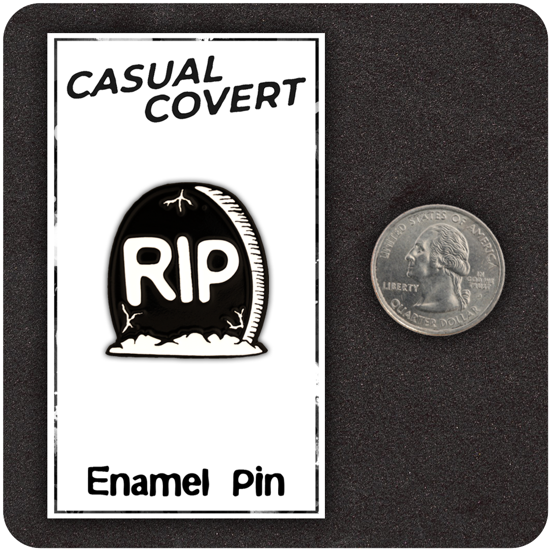 The Casual Covert RIP Enamel Pin next to a quarter to show it's size.