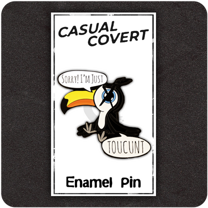 Cheeky enamel pin shaped like a cartoon toucan with a bold orange beak, making a sarcastic face and saying “Sorry! I’m Just TOUCUNT,” displayed on a black background.