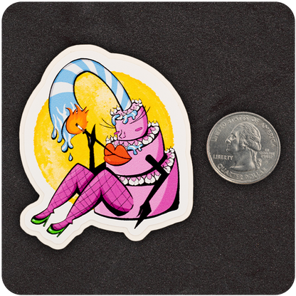 A colorful vinyl sticker featuring a cheeky anthropomorphic birthday cake character. The cake is pink with frosting layers, large red lips, and fishnet-clad legs in green heels. A tall, striped candle arches over the character, dripping wax toward a lit matchstick. The sticker is set against a textured black background with a bright yellow circle behind the character. A U.S. quarter is placed next to the sticker for scale.