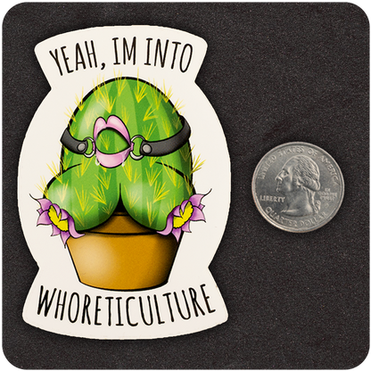 A humorous vinyl sticker featuring a green cactus shaped like a bottom, with spines, flowers, and a pink bondage harness. The cactus sits in a brown flower pot. Text above and below the image reads, “Yeah, I’m into WHORETICULTURE.” A U.S. quarter is placed beside the sticker to show scale. The background is a dark, textured surface.