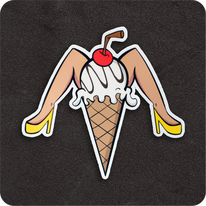 A fun, cheeky vinyl sticker featuring a pin-up-inspired ice cream cone design. The scoop is vanilla with white drizzle, topped with a bright red cherry and a brown straw. The cone has light-skinned legs in bright yellow high heels, posed playfully. Set against a black background.